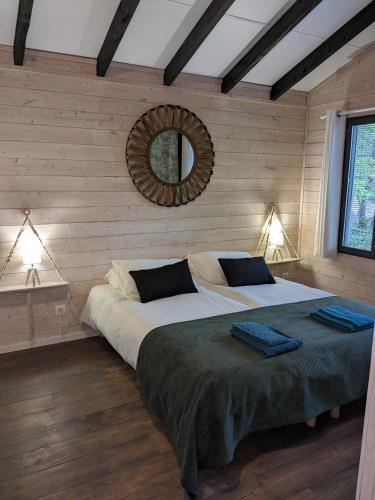 une chambre avec un grand lit avec un miroir au mur dans l'établissement Lodge Hérisson avec Spa privatif, à Biron