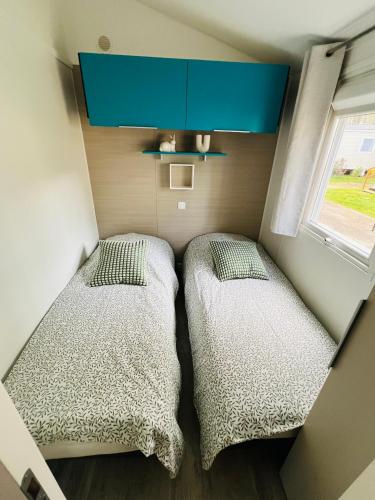 deux lits dans une petite pièce avec une fenêtre dans l'établissement Mobil Home MarieVa 