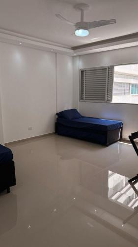 een slaapkamer met een blauw bed in een kamer met een raam bij Apê da divisa in São Vicente