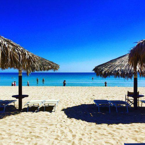 a beach with chairs and umbrellas and the ocean at Hotel Noto Marina Vista Mare in Noto Marina