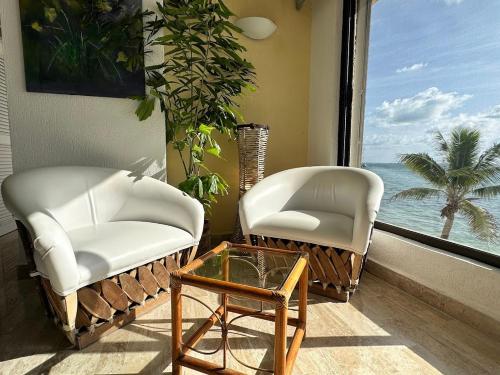 two chairs and a coffee table in front of a window at Cancun condo en la playa de Puerto Juarez in Cancún