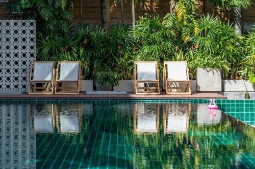three lounge chairs sitting next to a swimming pool at Buasri Boutique Patong in Patong Beach