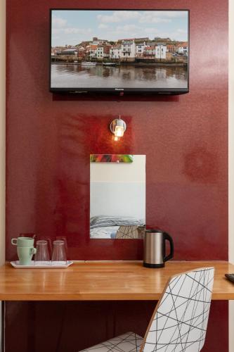 a television hanging on a wall with a wooden table at The Town House in Whitby