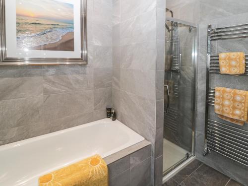 a bathroom with a bath tub and a shower at Sunflowers in Whitley Bay