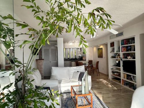 a living room with a white couch and some plants at Cancun condo en la playa de Puerto Juarez in Cancún