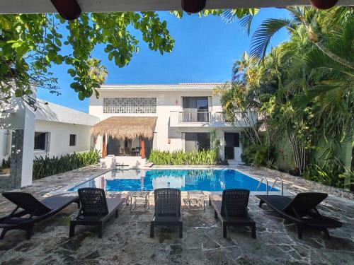 a swimming pool with chairs and a house at Casa Armonia , apartments with pool in Cozumel