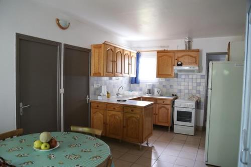 - une cuisine avec des placards en bois et une table avec des fruits dans l'établissement Maison 6 personnes sur grand terrain 100 m plage - V0261, à Vias