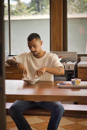 a man sitting at a table eating food from a bowl at Ceiba Hostel in Fortuna
