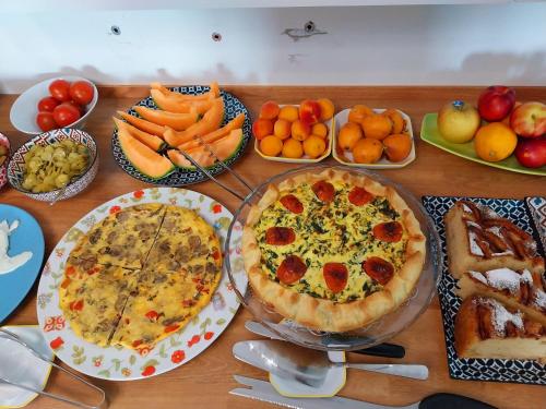 a wooden table topped with pizzas and fruits and vegetables at Villa Bellavista Alba, B&B in Alba