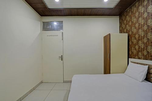 a bedroom with a white bed and a door at Super Hotel O Krishna Guest House & PG in Ludhiana