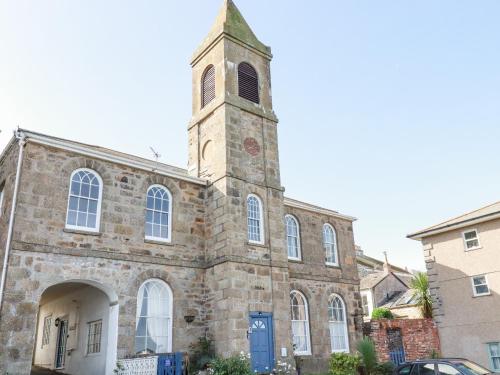 an old stone church with a clock tower on top at 2 Bell Tower in Penzance