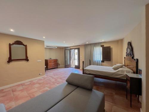 a bedroom with a bed and a couch and a mirror at Cal Gabarró - Casa para 12 con piscina, WiFi, AC y BBQ in Vilanova de Meyá
