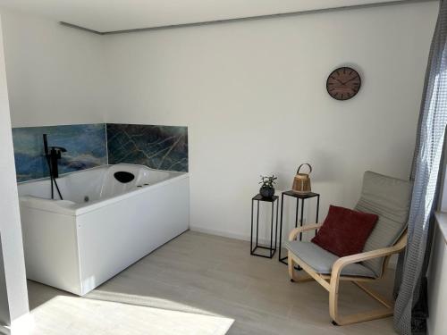 a bathroom with a tub and a chair and a clock at RheinSchatz Apartments 3 in Oberwesel