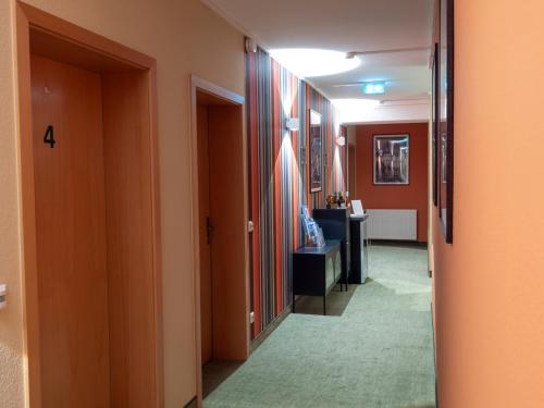 a hallway with a room with orange walls and a mirror at Altstadthotel "Garni" Grimma in Grimma
