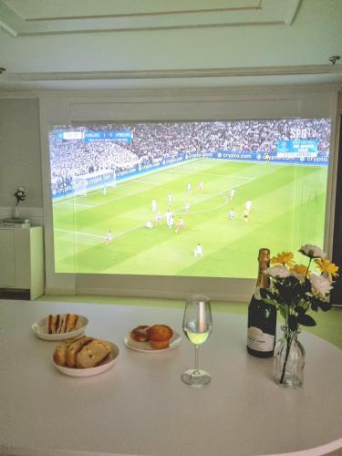 a table with plates of food and a television with a soccer game at StayHo in Daejeon