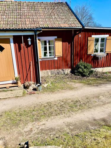 a red house with a red door and windows at Fairy Lake Retreat! Uniquely Located House with Dock! in Bålsta
