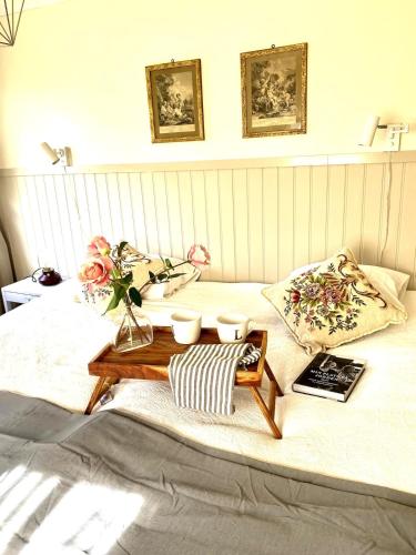 a bed with a table and flowers on it at Fairy Lake Retreat! Uniquely Located House with Dock! in Bålsta