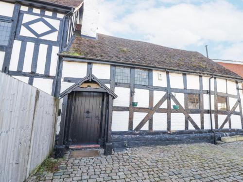 an old white and black building with a door at Wyre Court Cottage in Bewdley
