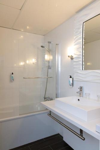 a white bathroom with a sink and a shower at Hôtel Atalante - Relais Thalasso & Spa in Sainte-Marie-de-Ré
