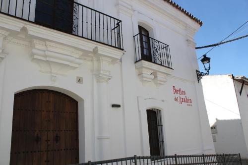 a white building with a wooden door and a balcony at Pórtico del Azahín in Cazalla de la Sierra