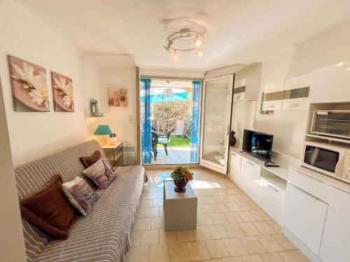 un salon avec un canapé et une télévision dans l'établissement Studio en rez-de-jardin à Bandol - parking, à Bandol