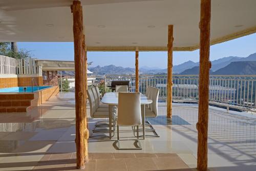 a table and chairs on a balcony with a view at Mountain Zen 2 Bed Ultimate Retreat with BBQ & Pool in Masāfī