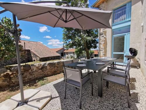 une table et des chaises avec un parasol sur une terrasse dans l'établissement Grand gîte de groupe le Val d'Allier confortable 15 personnes Saint-Haon Haute-Loire Auvergne, à Saint-Haon