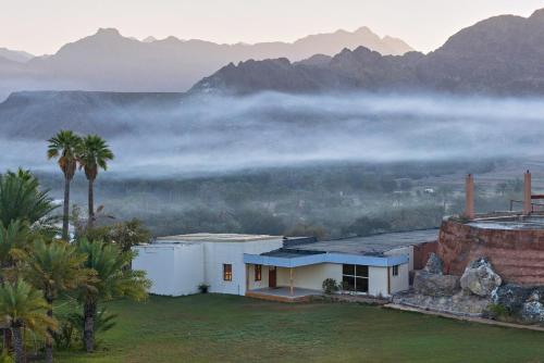a house with mountains in the background with fog at Mountain Zen 2 Bed Ultimate Retreat with BBQ & Pool in Masāfī