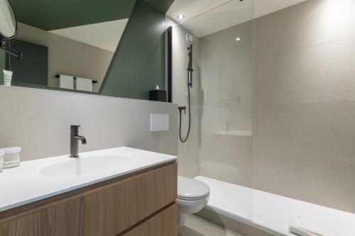 a bathroom with a sink and a toilet and a shower at Everness Hotel & Resort in Chavannes-de-Bogis