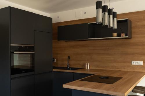 a kitchen with black cabinets and a wooden counter top at Andrea 's 4 seasons in Albrechtice v Jizerských horách