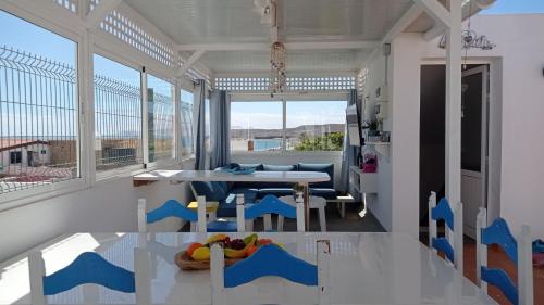 a dining room with a table and chairs and windows at Buena Fuerte Apartamentos Mari Giuli in Tarajalejo
