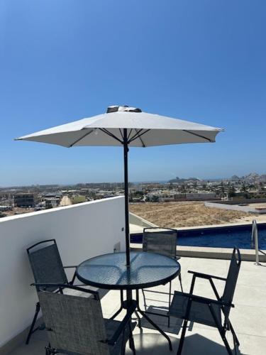 a table and chairs with an umbrella on a balcony at Cabo Manor - Boutique Condo in Cabo San Lucas
