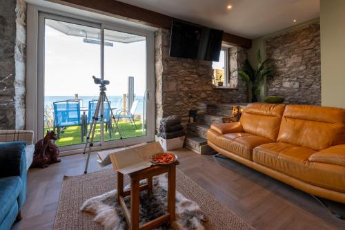 a living room with a leather couch and a large window at Bryn Glasfor in Barmouth