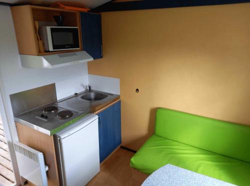 a small kitchen with a sink and a green couch at Camping 3 étoiles - efaicg in Auxonne