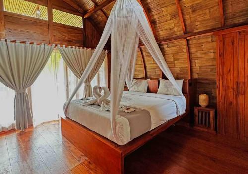 a bedroom with a bed with mosquito net at Lagoona Beach Bungalows - Eco Bungalows Batukaras in Batukaras