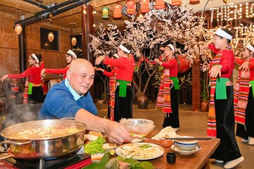 a man preparing food in front of a group of people at Hồ Đá Cổ Thiên Long Resort Hòa Bình in Hòa Bình