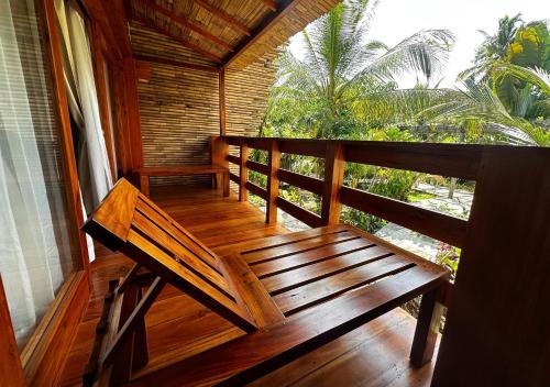 a wooden bench sitting on the porch of a house at Lagoona Beach Bungalows - Eco Bungalows Batukaras in Batukaras