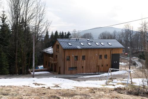 a large wooden building with a roof in the snow at Andrea 's 4 seasons in Albrechtice v Jizerských horách
