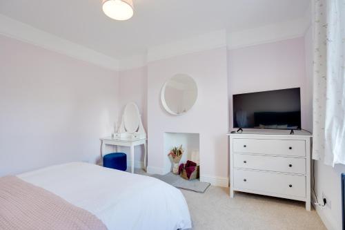 a white bedroom with a bed and a television at NEW The Procession Grade II Listed and Pet Friendly in Berwick-Upon-Tweed