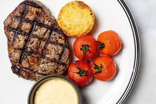 a plate of steak and tomatoes with a dipping sauce at Crowne Plaza Canberra by IHG in Canberra
