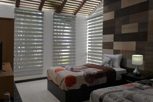 a bedroom with two beds and a window with blinds at HOTEL BOUTIQUE KRYSTAL in Quito