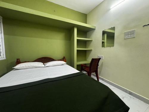 a green bedroom with a bed and a chair at Sri Arunachala Homestay in Tiruvannāmalai