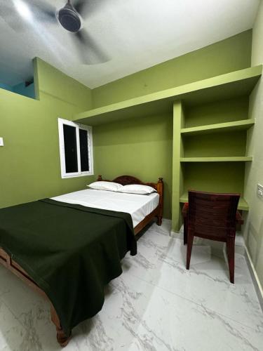 a green bedroom with a bed and a chair at Sri Arunachala Homestay in Tiruvannāmalai