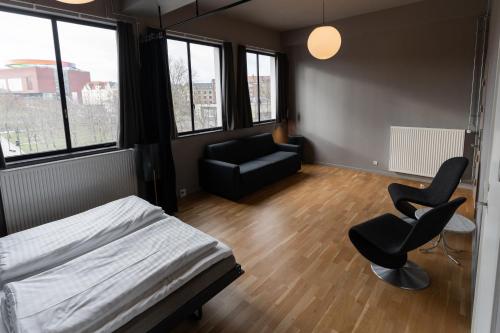 a bedroom with a bed and two chairs and a couch at Roberta's Society Aarhus in Aarhus