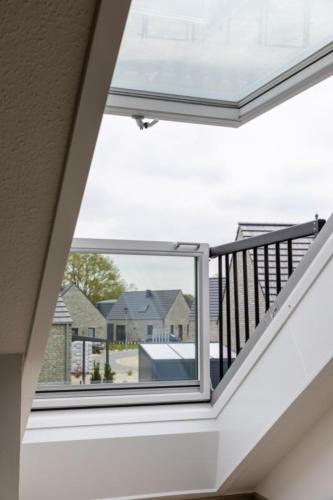 a room with a balcony with a view of houses at Ferienwohnung Sonnenstrahl am Harkebrügger See mit Sauna in Barßel