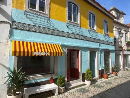 Un edificio colorido con un banco delante. en Casa da Heidi, en Lourinhã