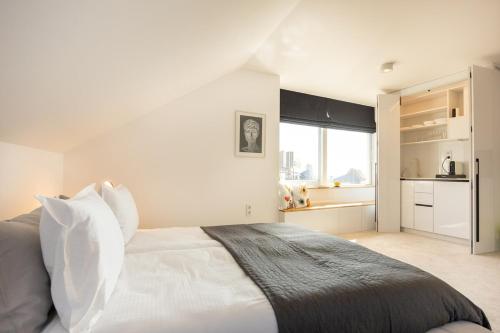 a white bedroom with a bed and a kitchen at Apartment Musala N 05 in Varna City