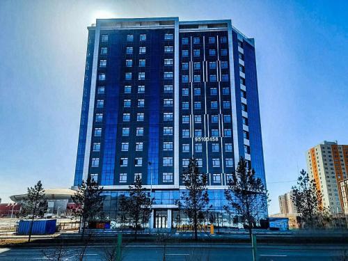 a tall blue building with trees in front of it at EBTM Apartments Hotel in Ulaanbaatar