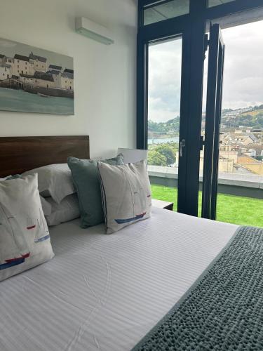 a bedroom with a bed with pillows and a large window at Riviera Apartments - Five Stylish Penthouse Apartments with Unrivalled Sea Views of Teignmouth, Shaldon, The Jurassic Coastline & The Teign Estuary in Teignmouth