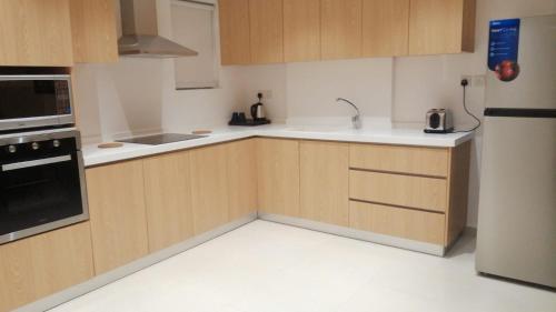 a kitchen with wooden cabinets and white counter tops at نخيل هجر للشقق الفندقية Nakheel Hajr Hotel Apartments in Al Hofuf